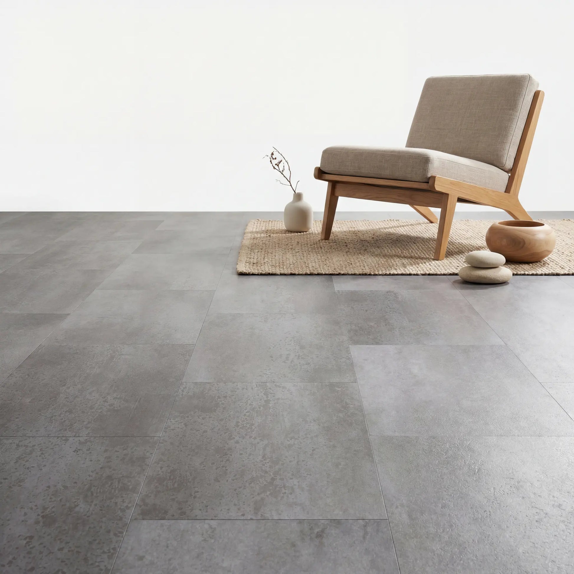 Lichte fauteuil op Aura Terrena Griseus betonlook pvc vloer, minimalistisch interieur.